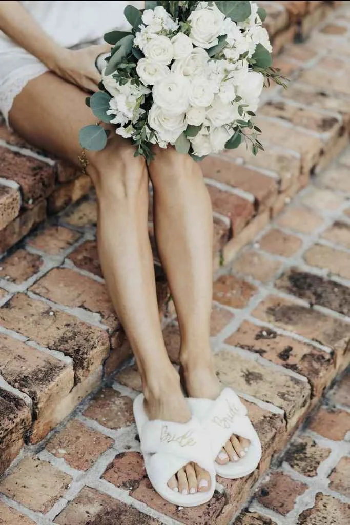 Magnolia Valley Weddings & Events bride’s feet with white flowers and greenery are captured in detail.