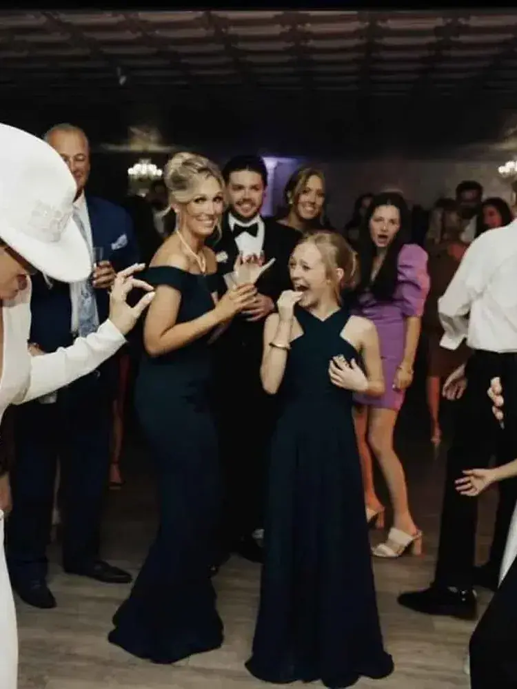 A woman in a black dress dances with friends at Magnolia Valley Weddings & Events wedding.
