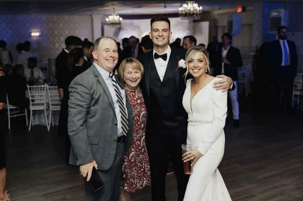 Magnolia Valley Weddings & Events man in a suit stands with two women during a wedding celebration.