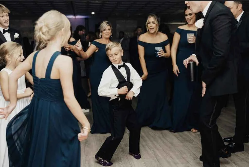 Magnolia Valley Weddings & Events young boy in a tuxedo dances with his mother at a wedding.