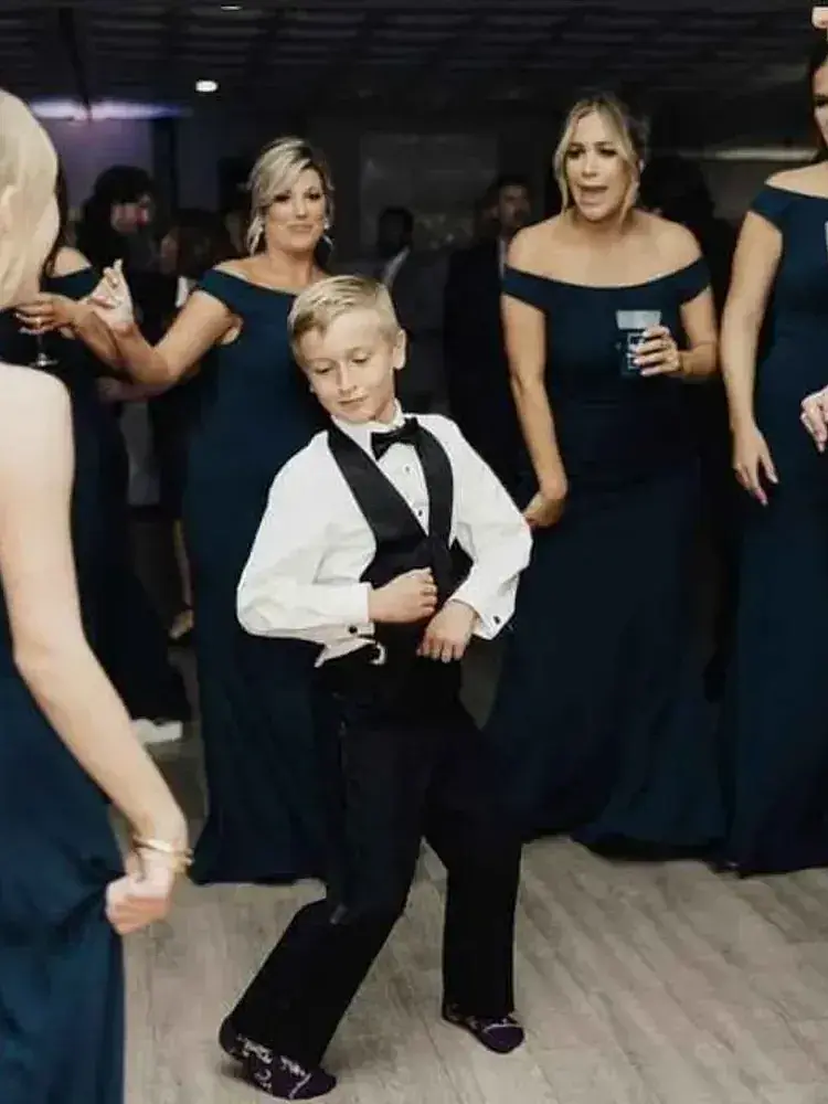 Magnolia Valley Weddings & Events young boy in a tuxedo dances with his mother at a wedding.